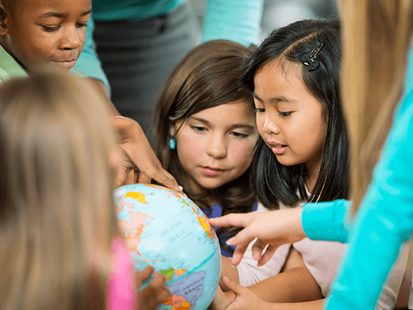 Multi-cultural children looking at a world globe